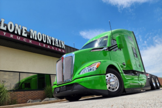 Green 2026 Kenworth T680 outside Lone Mountain Truck Leasing office building in Carter Lake, Iowa