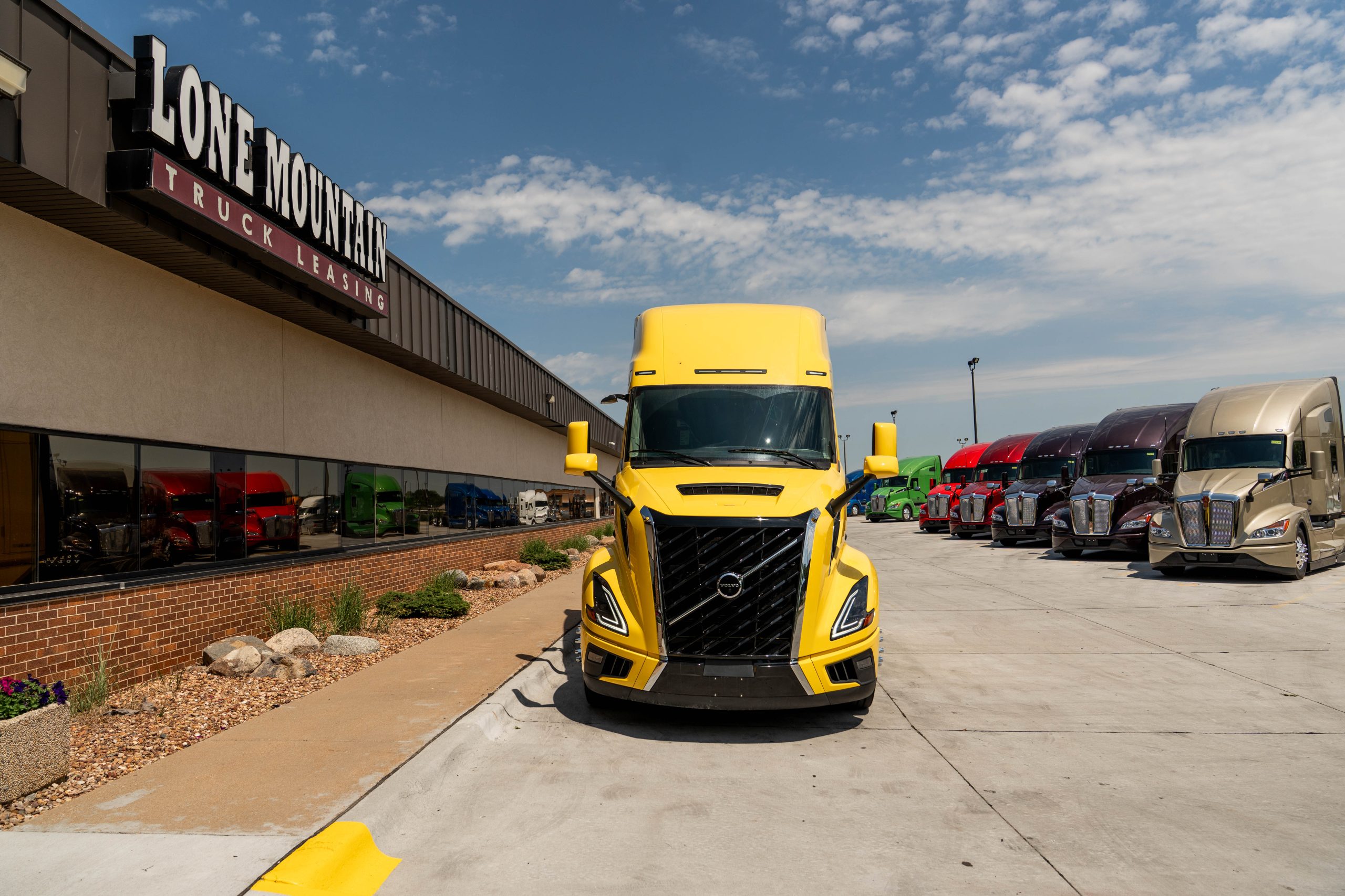 view of front of a yellow 2027 Volvo VNL 860 parked outside Lone Mountain Truck Leasing's Carter Lake, Iowa headquarters