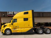 view of driver's side of a yellow 2027 Volvo VNL 860 parked outside Lone Mountain Truck Leasing's Carter Lake, Iowa headquarters