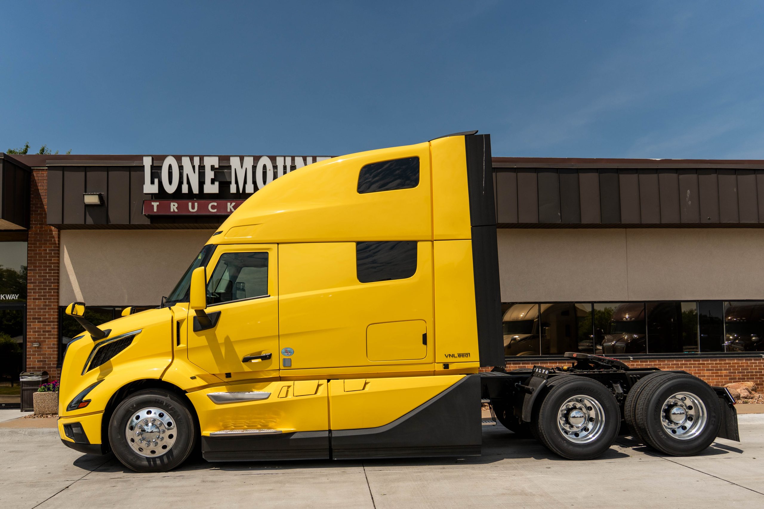 view of driver's side of a yellow 2027 Volvo VNL 860 parked outside Lone Mountain Truck Leasing's Carter Lake, Iowa headquarters