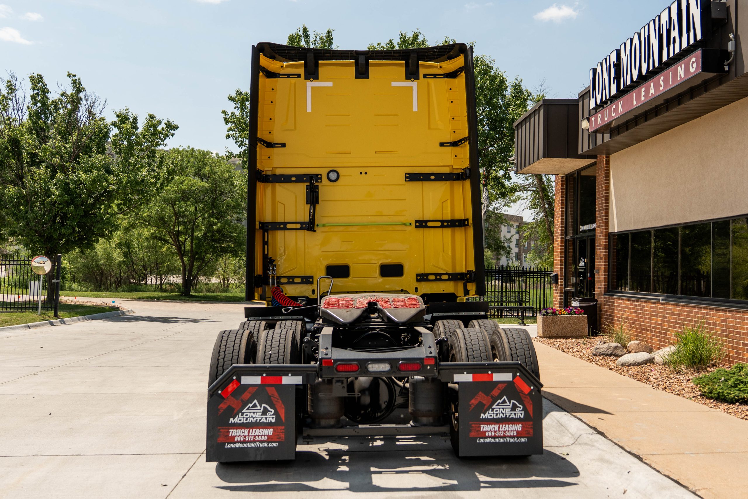 view of back of a yellow 2027 Volvo VNL 860 parked outside Lone Mountain Truck Leasing's Carter Lake, Iowa headquarters