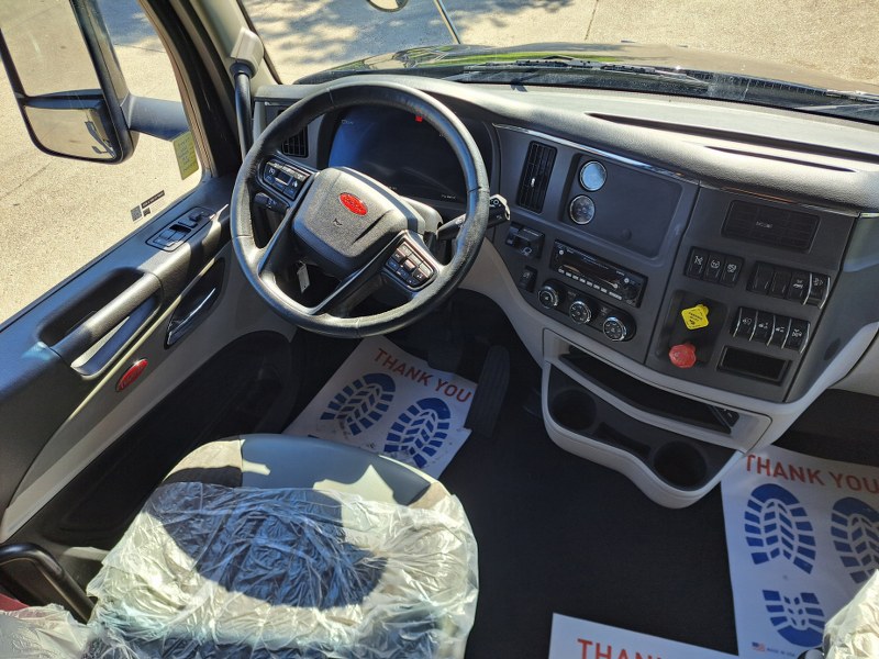 Driver side with steering wheel and dash inside a 2022 Black Peterbilt 579