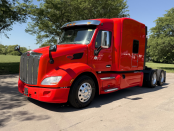 Driver side and front of a red 2022 Peterbilt 579 mid-roof