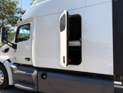 Driver side of a white 2022 Peterbilt 579 with emergency door open