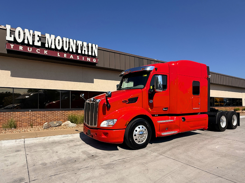 Red 2022 Peterbilt 579 mid-roof semi truck parked outside Lone Mountain Truck Leasing's Carter Lake, Iowa headquarters